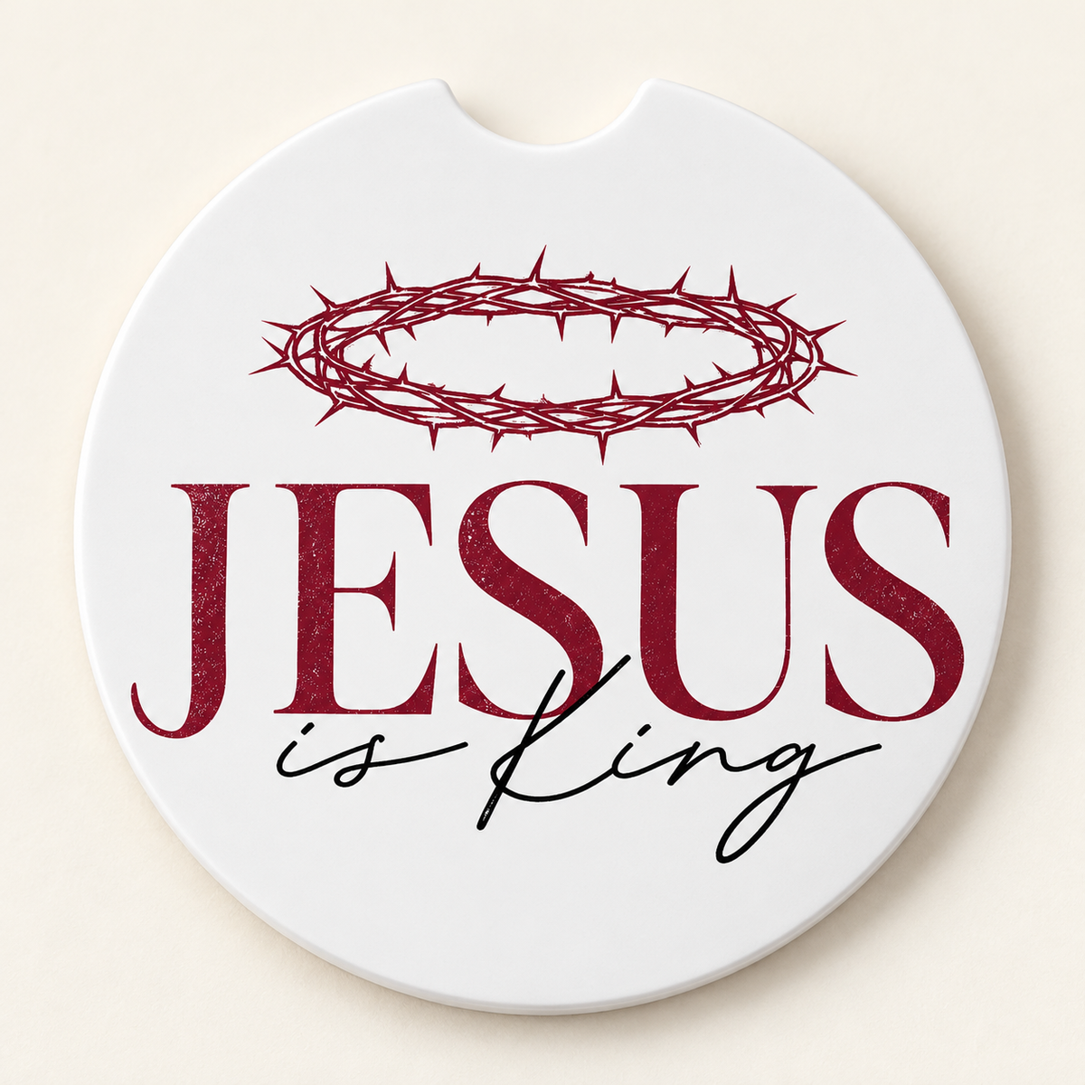 Round white car coaster with a finger notch featuring a burgundy crown of thorns above burgundy JESUS lettering and black is King script.