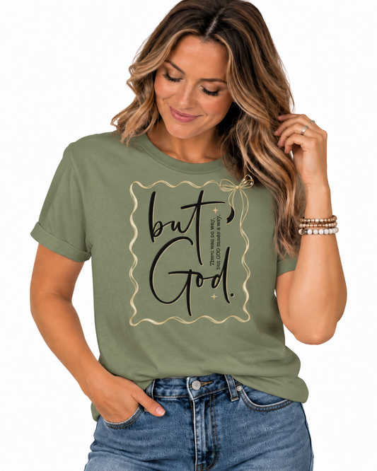 Olive green Christian T-shirt featuring “But God” with “There was no way, but God made a way,” black script, delicate gold frame, bow, and faith-inspired accents.