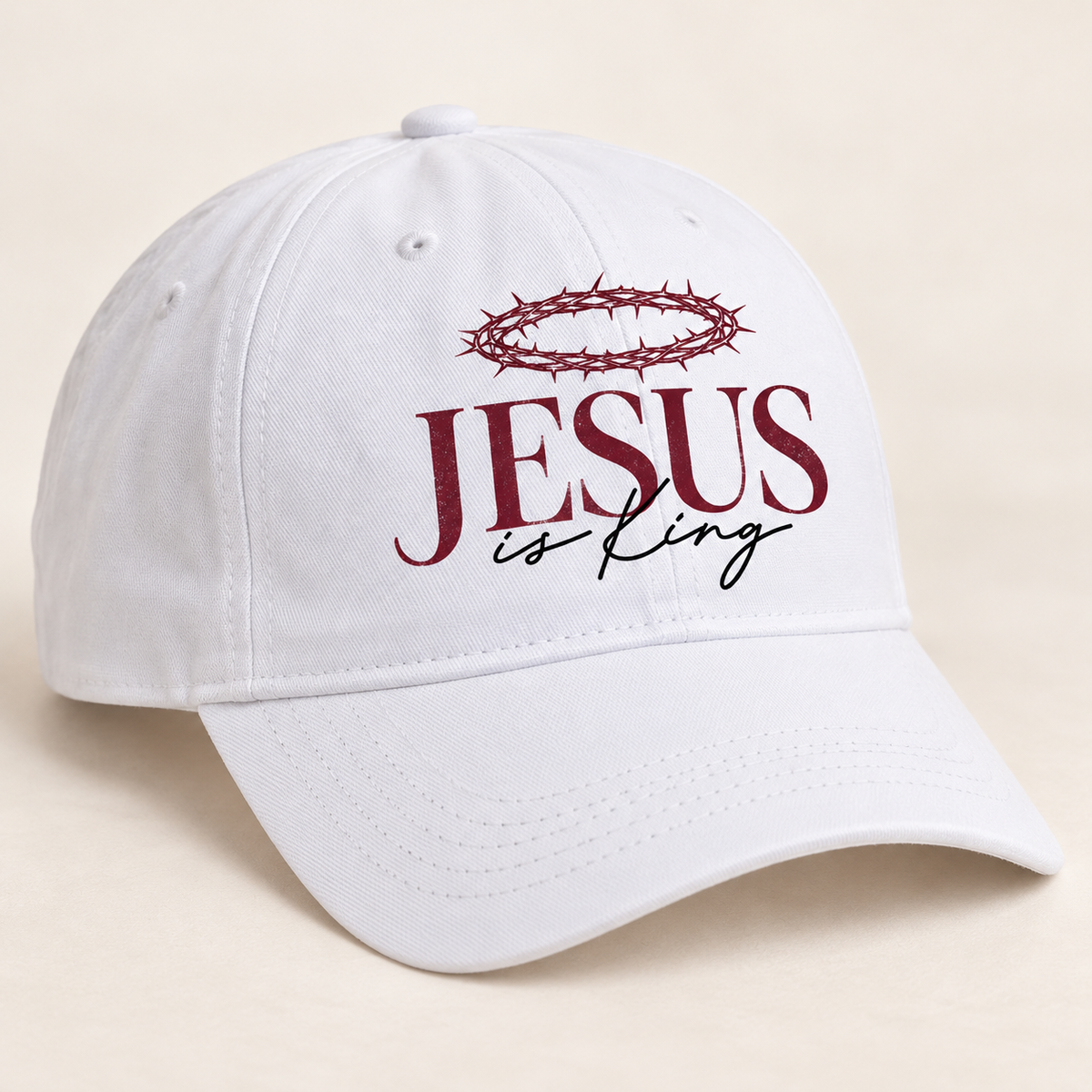 White ball cap with a curved brim featuring a burgundy crown of thorns above burgundy JESUS lettering and black is King script.