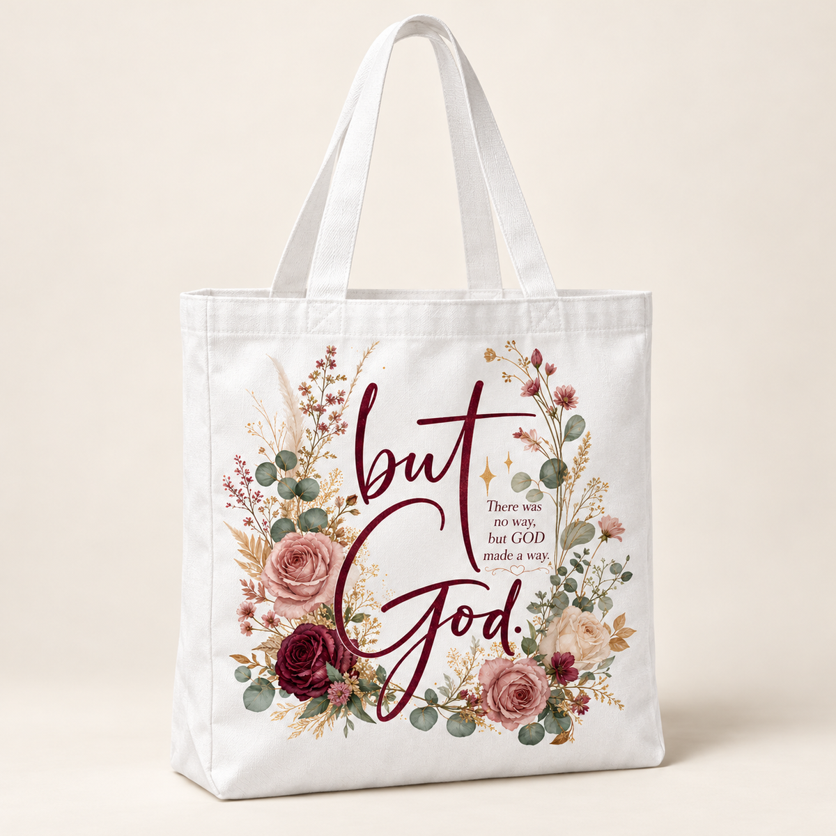 White tote bag with long handles, burgundy But God lettering, blush and cream roses, sage greenery, and an encouraging faith message.