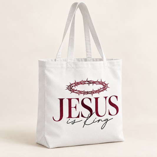 White tote bag with long handles featuring a burgundy crown of thorns above burgundy JESUS lettering and black is King script